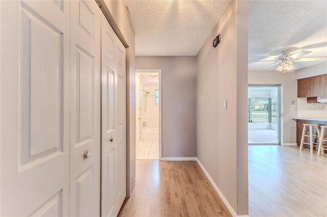 corridor with a textured ceiling and light wood-type flooring