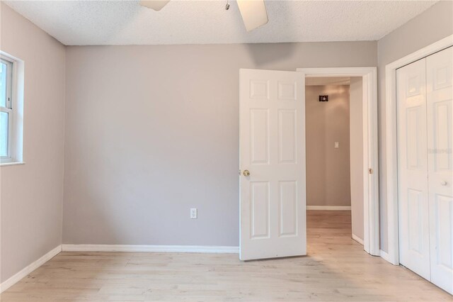 interior space featuring ceiling fan, light wood-type flooring, and a textured ceiling