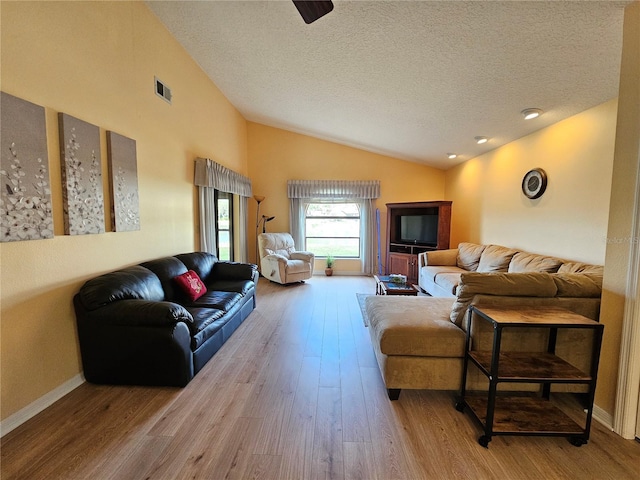 living room featuring a textured ceiling, light hardwood / wood-style flooring, and vaulted ceiling