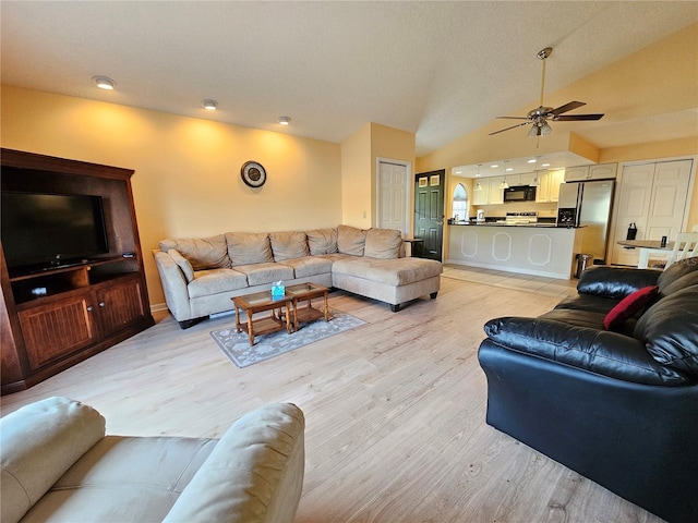 living room featuring ceiling fan, lofted ceiling, and light wood-type flooring