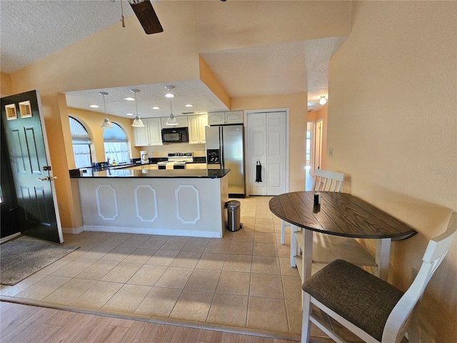9163 Lingrove Rd, Weeki Wachee, FL 34613 - kitchen with stainless steel refrigerator with ice dispenser, black microwave, electric range, vaulted ceiling, and a peninsula