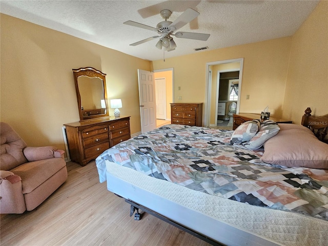 bedroom featuring ceiling fan, light hardwood / wood-style floors, and a textured ceiling