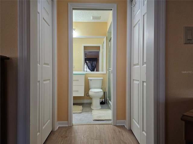 corridor featuring a textured ceiling and light hardwood / wood-style flooring