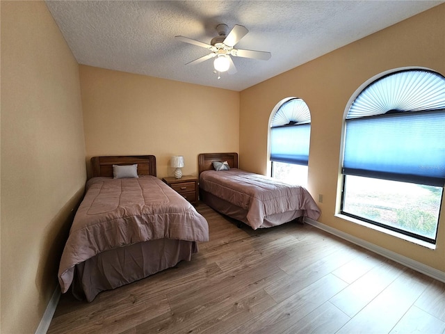 bedroom featuring ceiling fan, light hardwood / wood-style flooring, and a textured ceiling