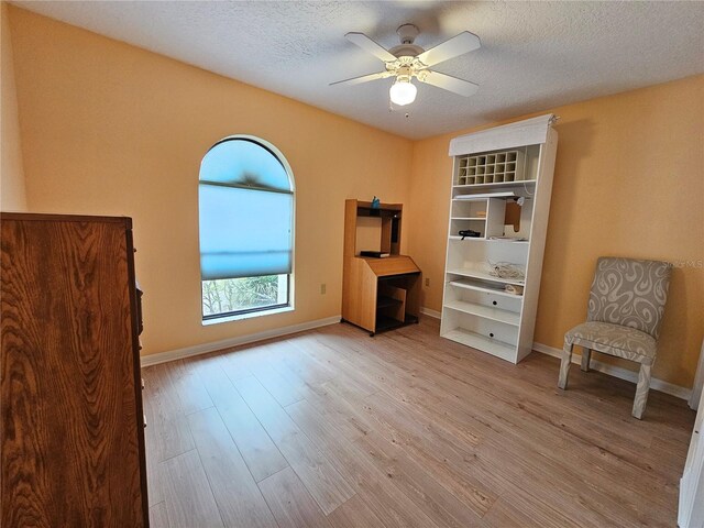 living area featuring ceiling fan, a textured ceiling, and light wood-type flooring