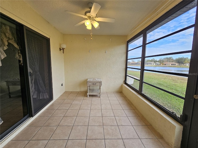 unfurnished sunroom with a water view and ceiling fan