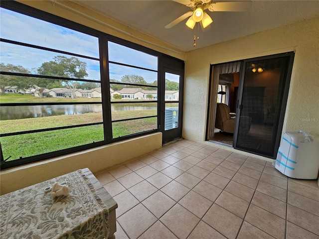 sunroom featuring a water view and ceiling fan