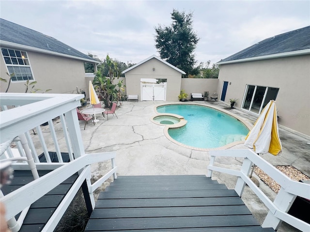 view of pool with a patio area, an in ground hot tub, and an outbuilding