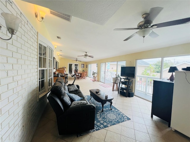 living room featuring ceiling fan, light tile patterned flooring, and brick wall