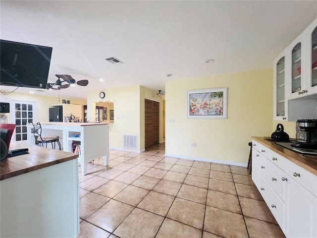 kitchen featuring butcher block counters, white cabinets, and light tile patterned flooring