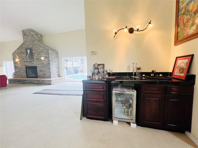 bar with light carpet, a fireplace, high vaulted ceiling, and beverage cooler