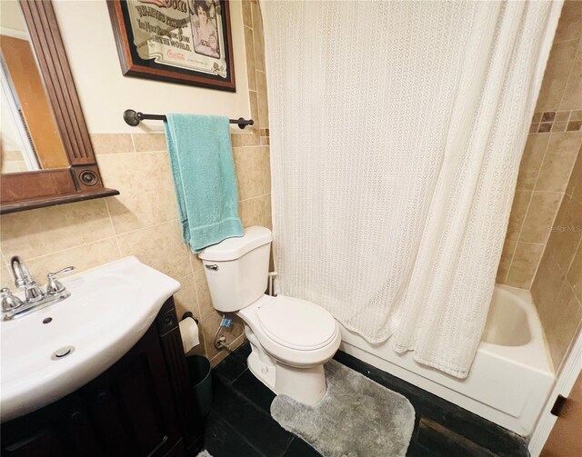 full bathroom with vanity, toilet, shower / bath combo with shower curtain, and tile walls