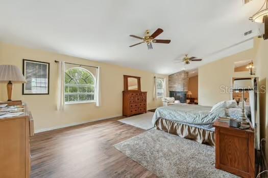 7941 Sycamore Dr, New Port Richey, FL 34654 - bedroom featuring wood finished floors, lofted ceiling, and a fireplace