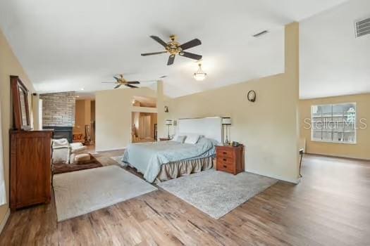 7941 Sycamore Dr, New Port Richey, FL 34654 - bedroom featuring lofted ceiling, wood finished floors, and a fireplace