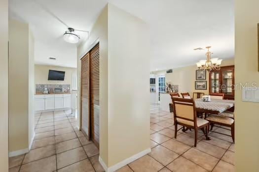 7941 Sycamore Dr, New Port Richey, FL 34654 - corridor with light tile patterned floors and a chandelier