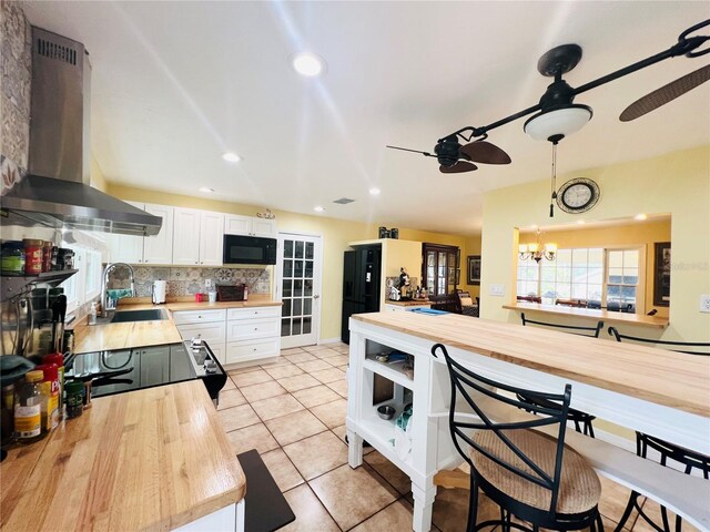 7941 Sycamore Dr, New Port Richey, FL 34654 - kitchen featuring island exhaust hood, butcher block countertops, black appliances, a ceiling fan, and white cabinets