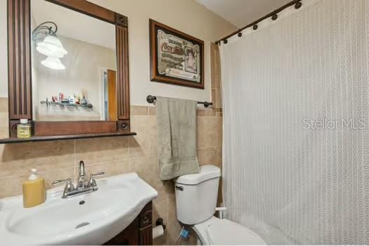 7941 Sycamore Dr, New Port Richey, FL 34654 - full bath with tile walls, a shower with curtain, vanity, and a wainscoted wall