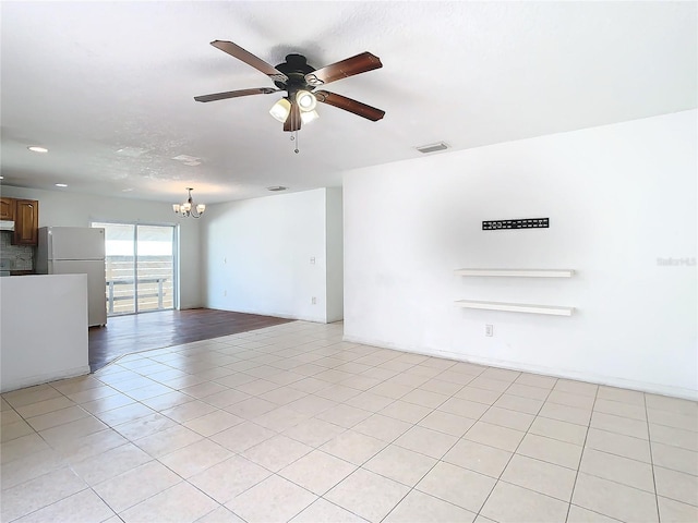 tiled spare room with ceiling fan with notable chandelier