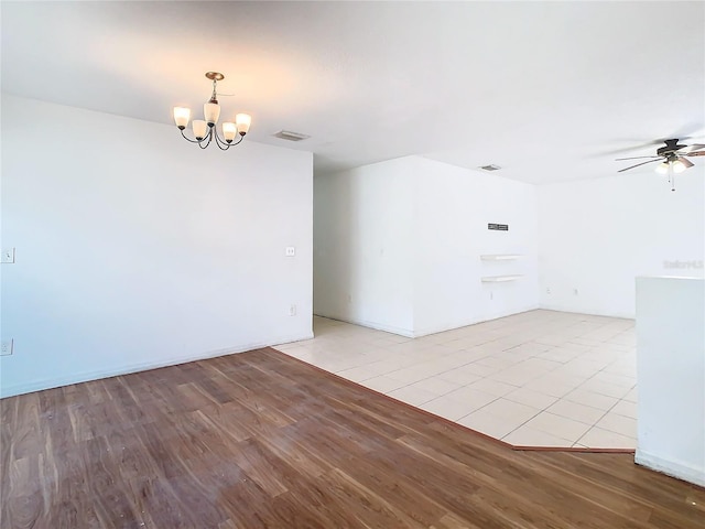 empty room with ceiling fan with notable chandelier and light hardwood / wood-style flooring