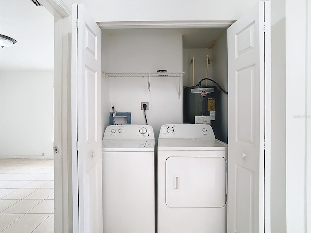 clothes washing area featuring washer and dryer, light tile patterned flooring, and water heater