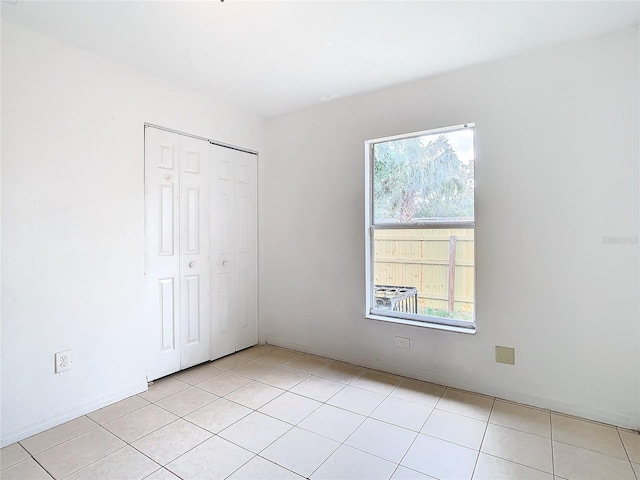 unfurnished bedroom with multiple windows, a closet, and light tile patterned flooring