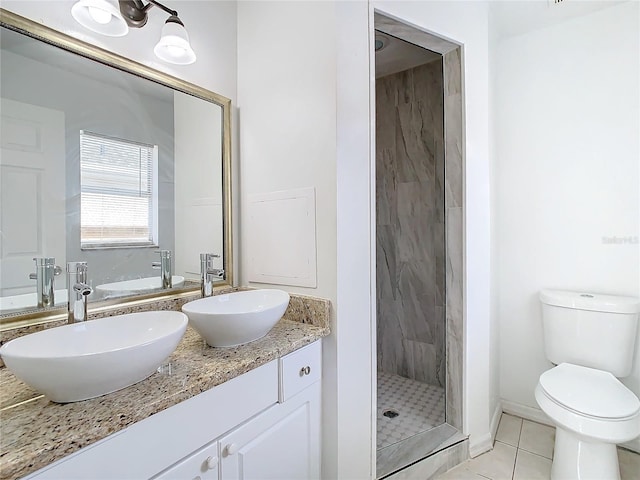 bathroom featuring toilet, tile patterned flooring, vanity, and tiled shower