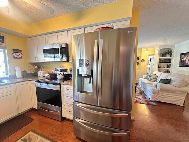 kitchen with white cabinets, a textured ceiling, stainless steel appliances, and dark hardwood / wood-style floors