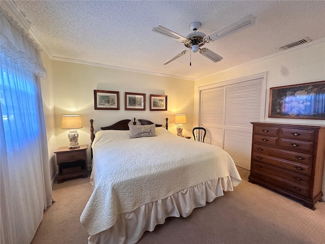 carpeted bedroom with a textured ceiling, a closet, ceiling fan, and crown molding