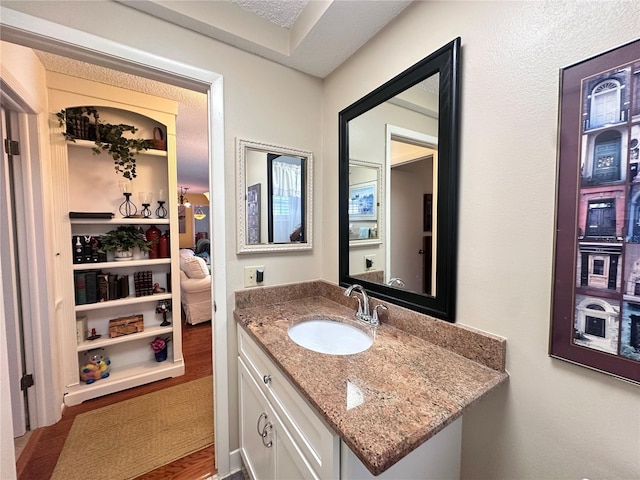 bathroom with hardwood / wood-style floors, vanity, and a textured ceiling