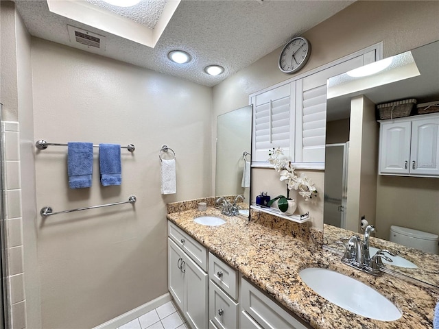 bathroom featuring tile patterned floors, vanity, a textured ceiling, a shower with door, and toilet