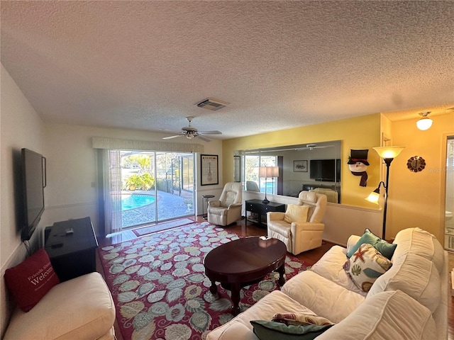 living room featuring ceiling fan, plenty of natural light, hardwood / wood-style floors, and a textured ceiling