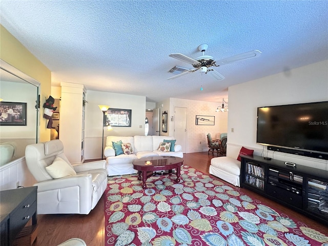 living room featuring a textured ceiling and ceiling fan with notable chandelier