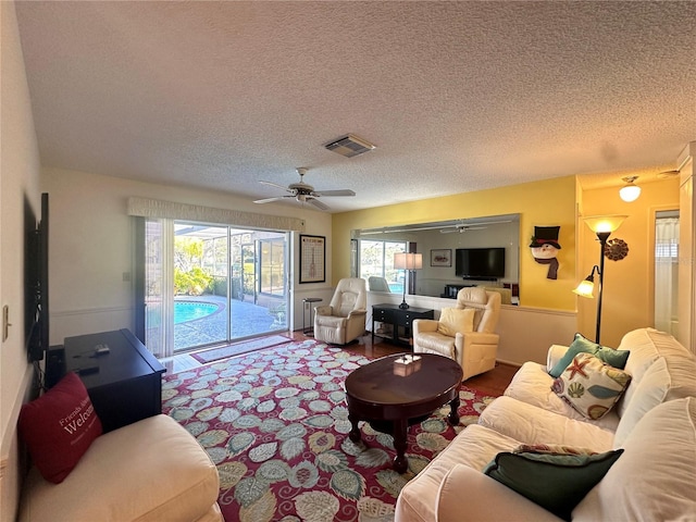 living room featuring a wealth of natural light, ceiling fan, and a textured ceiling