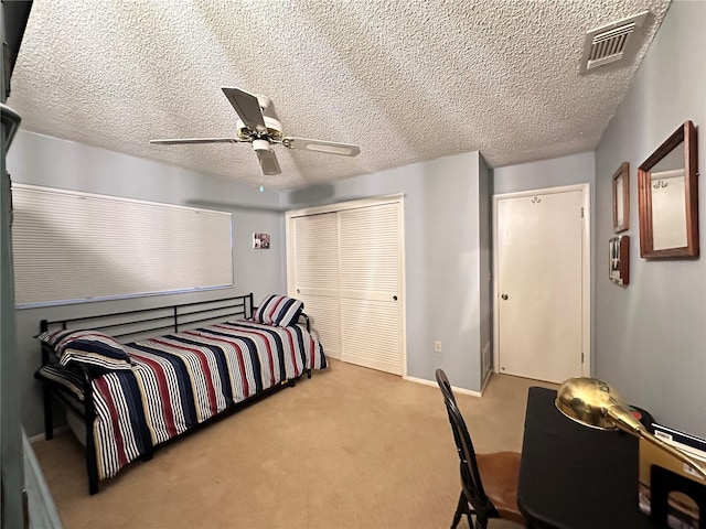 carpeted bedroom featuring ceiling fan and a textured ceiling