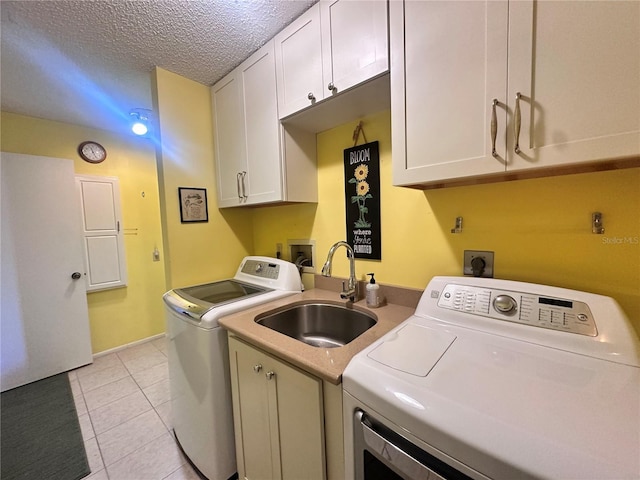 washroom with sink, cabinets, washing machine and dryer, a textured ceiling, and light tile patterned floors