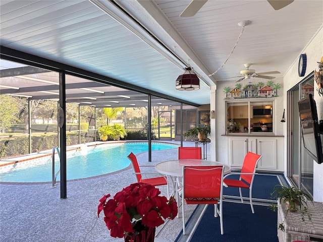 view of swimming pool with ceiling fan, a lanai, and a patio