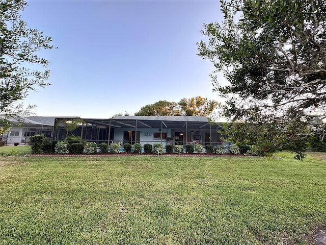 rear view of house with a yard and a lanai