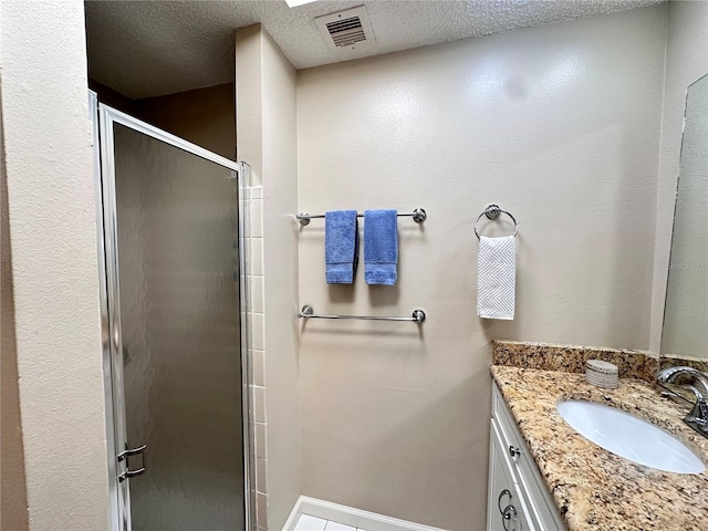 bathroom with a shower with door, vanity, and a textured ceiling