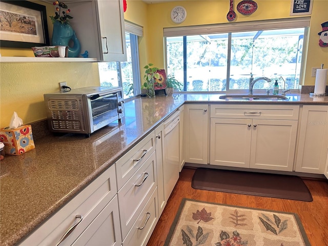 kitchen with white cabinets, sink, white dishwasher, and dark wood-type flooring