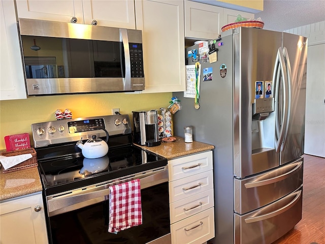 kitchen featuring white cabinets, light stone countertops, stainless steel appliances, and dark hardwood / wood-style floors