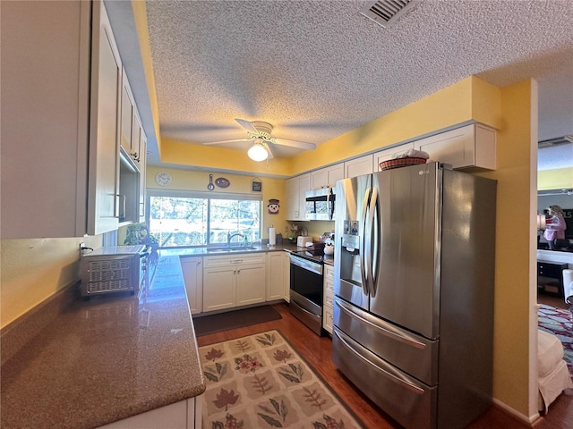 kitchen with sink, dark hardwood / wood-style floors, ceiling fan, white cabinetry, and stainless steel appliances