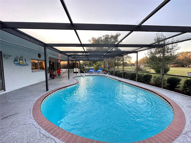 pool at dusk with a patio area and a lanai