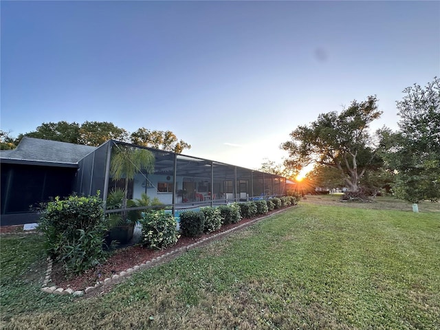 yard at dusk featuring a lanai