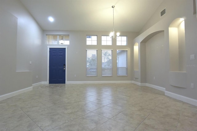 empty room featuring light tile patterned flooring, high vaulted ceiling, and a chandelier