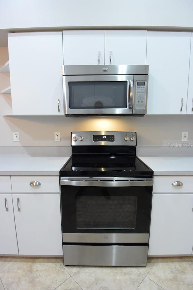 kitchen with white cabinets, appliances with stainless steel finishes, and light tile patterned floors