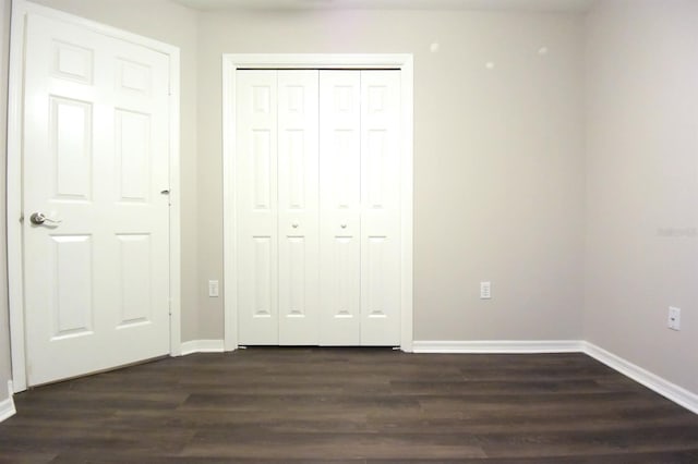 unfurnished bedroom with a closet and dark hardwood / wood-style flooring