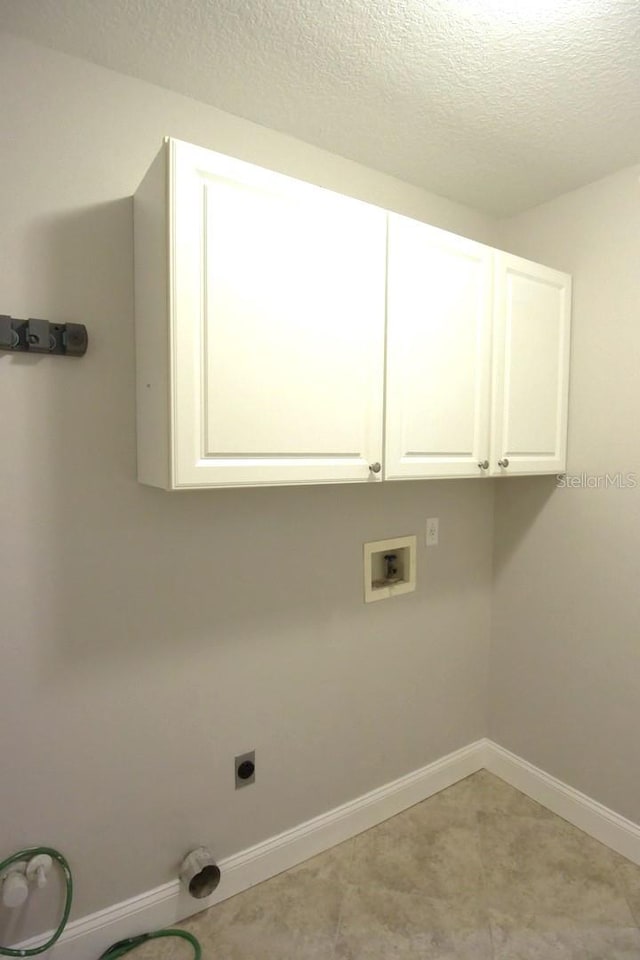 clothes washing area featuring electric dryer hookup, hookup for a washing machine, cabinets, and a textured ceiling