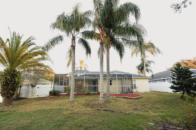 back of property with a yard and glass enclosure