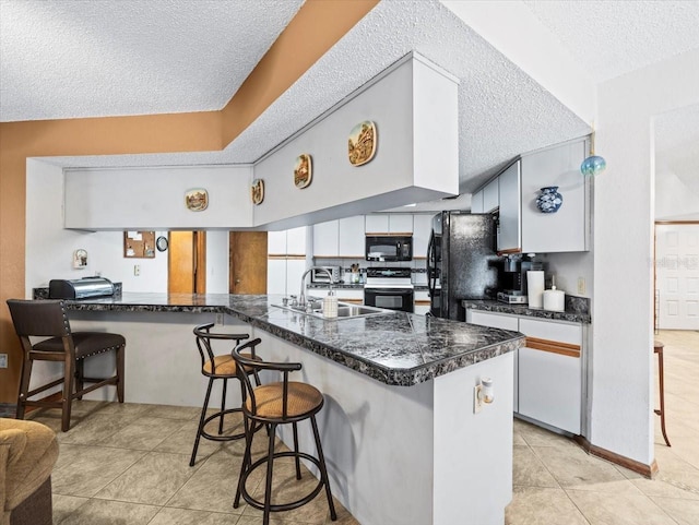 kitchen featuring black appliances, kitchen peninsula, and a breakfast bar area