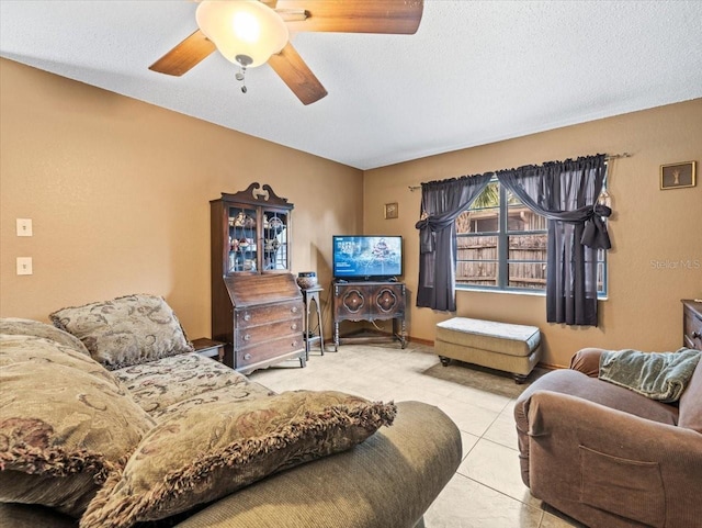 living room with ceiling fan, light tile patterned floors, and a textured ceiling